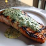 A perfectly cooked piece of Grilled Salmon Fillets with Lemon-Dill Sauce resting on a white plate.