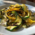 Close-up of perfectly charred Grilled Zucchini and Yellow Squash Ribbons served on a white plate.