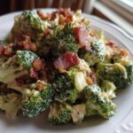 A close-up serving of Hearty Broccoli Salad with Bacon and Cheddar Cheese, coated in creamy dressing.