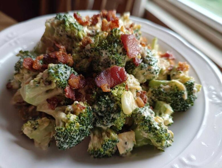 A close-up serving of Hearty Broccoli Salad with Bacon and Cheddar Cheese, coated in creamy dressing.