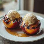 Two halves of Honey Grilled Peaches topped with scoops of vanilla ice cream and drizzled with honey.