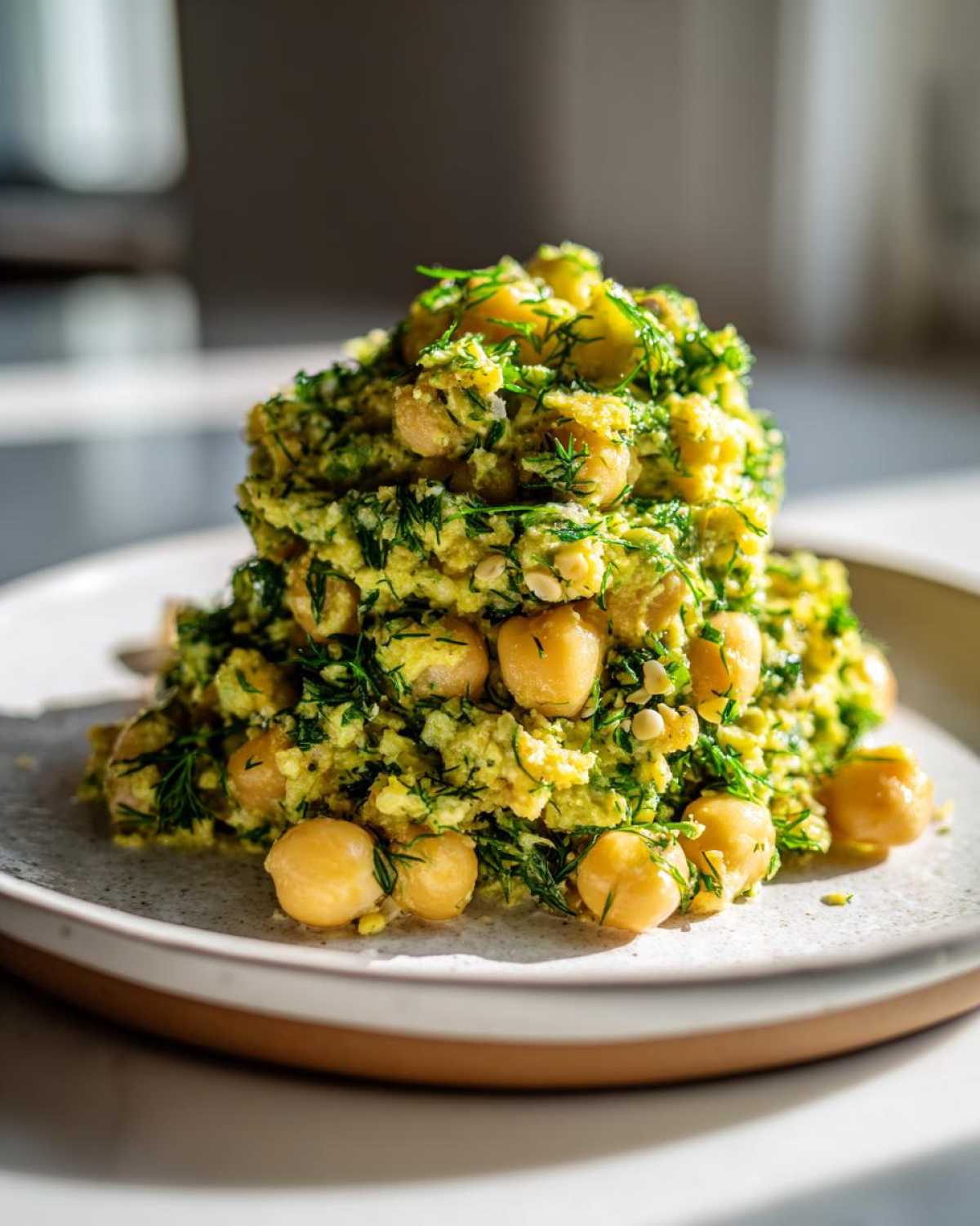 A mound of Lemony Chickpea Salad with Herbs, featuring whole chickpeas and finely chopped green herbs, served on a light plate.