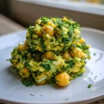 A mound of vibrant Lemony Chickpea Salad with Herbs, featuring whole chickpeas and finely chopped green herbs on a white plate.