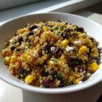 Close-up of a vibrant Mediterranean Quinoa Salad with Black Beans and Corn, mixed with feta cheese and herbs.