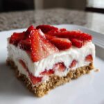 A close-up of a single serving slice of No-Bake Strawberry Heaven Dessert on a white plate.