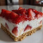 Close-up of a slice of No-Bake Strawberry Heaven Dessert featuring a graham cracker crust, creamy filling, and strawberry topping.