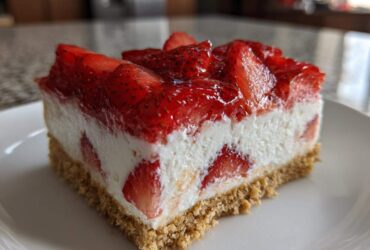 Close-up of a slice of No-Bake Strawberry Heaven Dessert featuring a graham cracker crust, creamy filling, and strawberry topping.