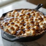 Close-up of hot Ooey-Gooey S'mores Dip baked in a cast iron skillet with perfectly toasted marshmallows.