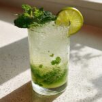 A tall glass holding The Perfect Classic Mojito Cocktail, garnished with fresh mint sprigs and a lime wheel.