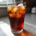 Tall glass filled with dark, cold Perfect Southern Sweet Iced Tea and ice cubes, showing condensation droplets.