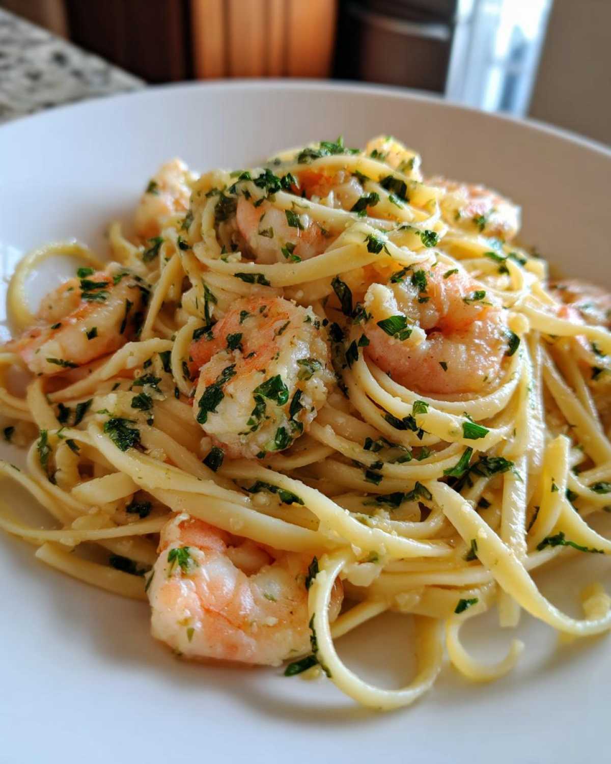Close-up of linguine pasta tossed with pink shrimp in a garlic butter sauce and topped with fresh parsley, a serving of Quick Garlic Butter Shrimp Scampi Pasta.