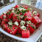 Close-up of cubed watermelon mixed with feta cheese crumbles and fresh mint in a white bowl, highlighting the Refreshing Watermelon Feta Salad.