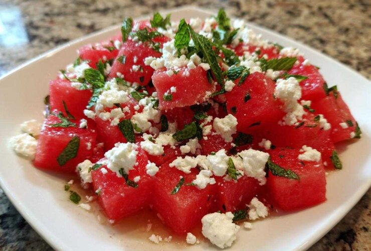 Close-up of a plate featuring Refreshing Watermelon Feta Salad with chunks of red watermelon, crumbled white feta cheese, and fresh mint leaves.