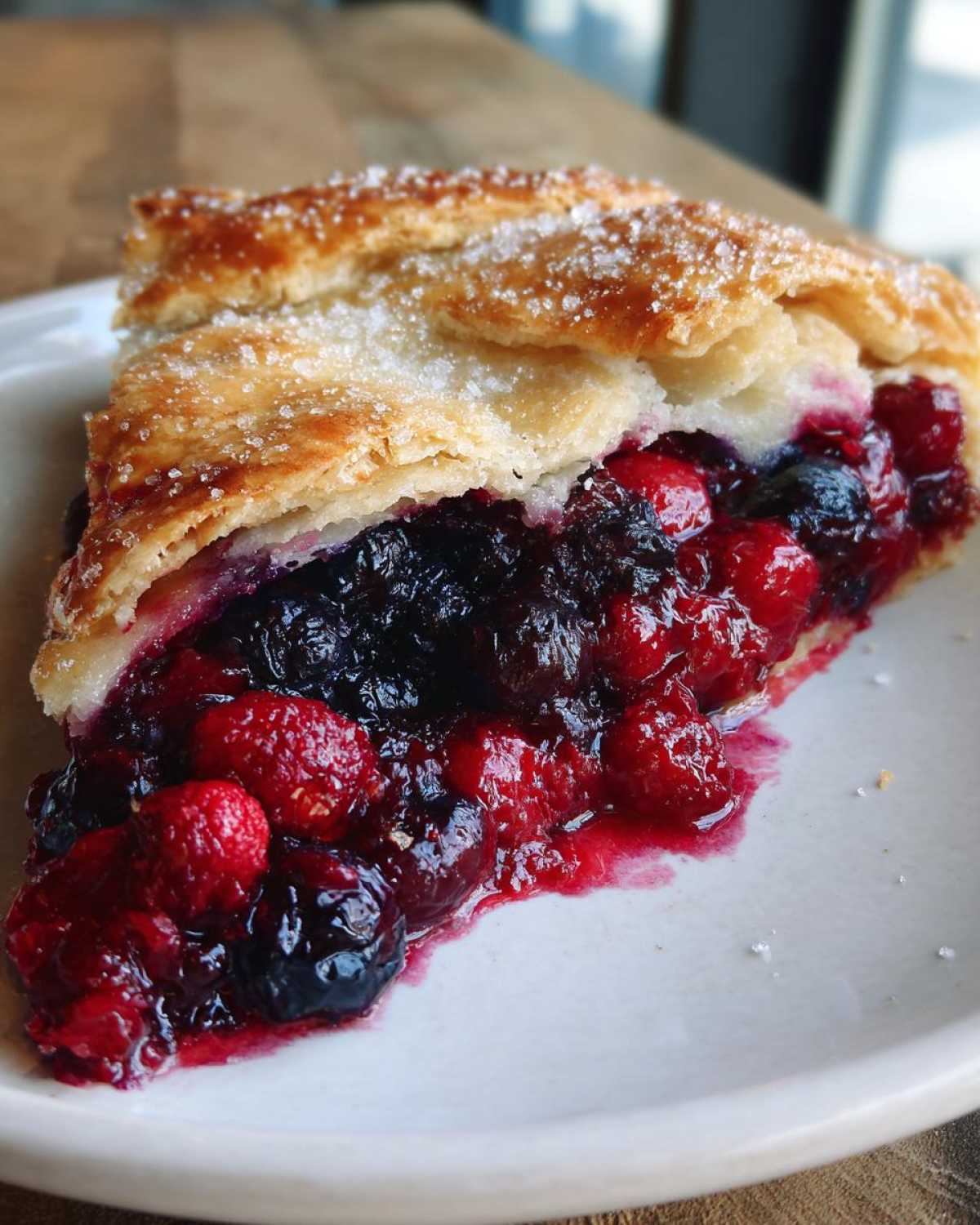 Close-up of a juicy slice of Rustic Summer Berry Galette showing mixed berries and a flaky, sugared crust.