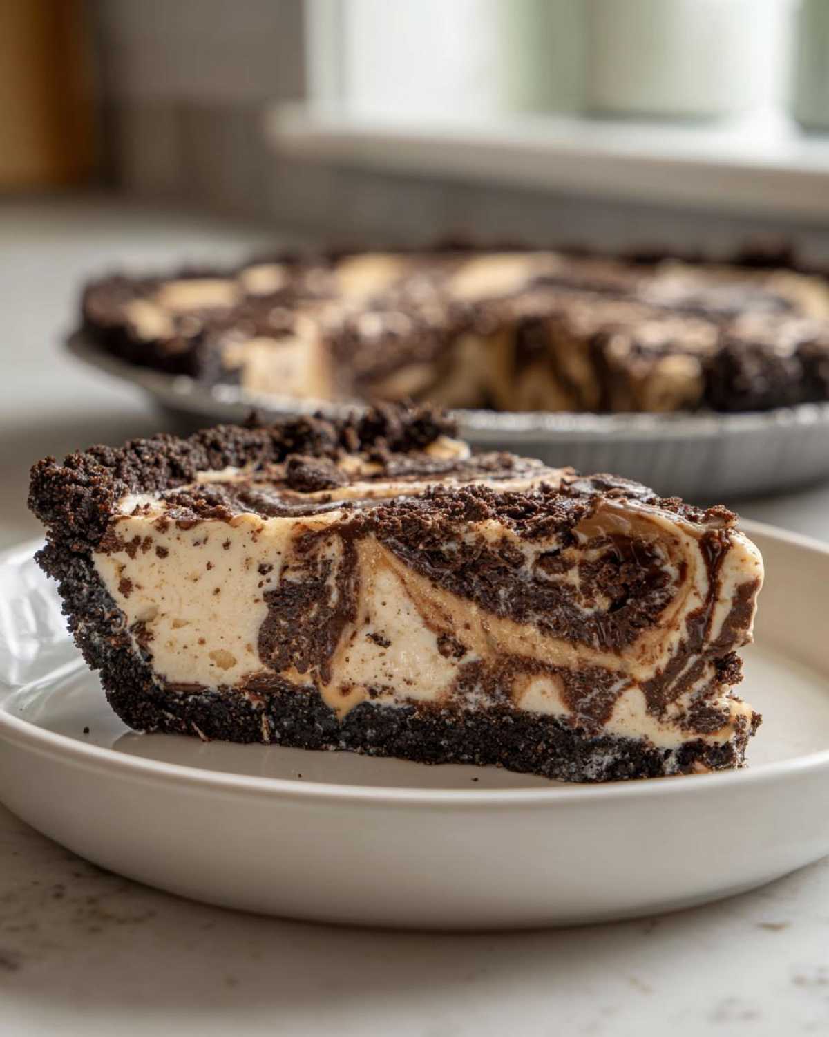 A close-up slice of Peanut Butter Fudge Ice Cream Pie with a dark chocolate crust and swirled filling.