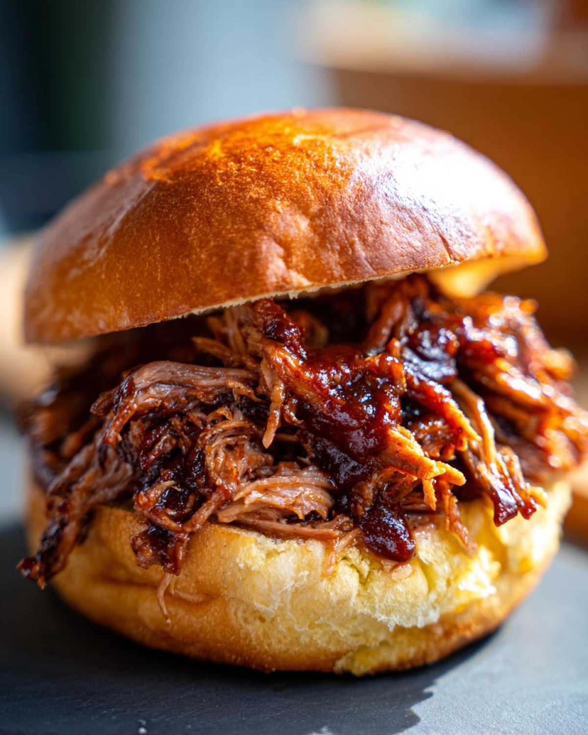 Close-up of a delicious Smoky BBQ Pulled Pork Sandwich piled high on a toasted brioche bun.