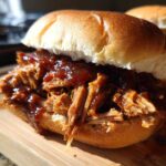 A close-up of a delicious Smoky BBQ Pulled Pork Sandwich piled high on a soft brioche bun, glistening with sauce.