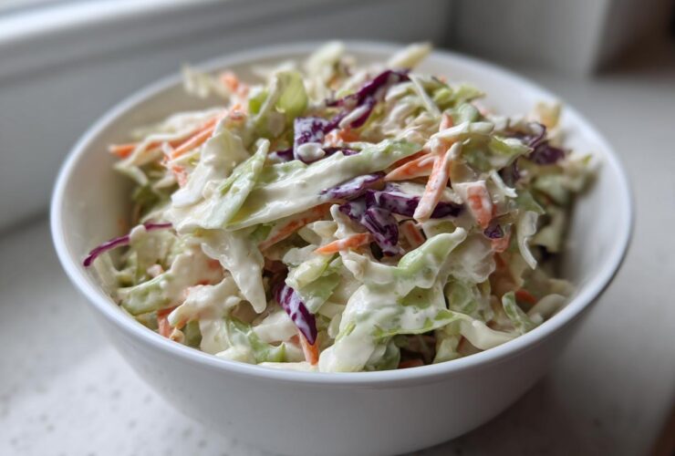 A white bowl filled with fresh Southern Style Creamy Coleslaw featuring shredded cabbage and carrots in a rich dressing.
