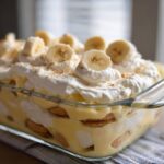 Close-up of Southern Style Layered Banana Pudding with vanilla wafers, custard, and whipped cream topped with banana slices.
