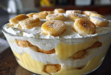 Close-up of Southern Style Layered Banana Pudding featuring layers of vanilla wafers, custard, and whipped cream, topped with sliced bananas.