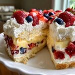 Cross-section view of a layered Summer Berry Trifle with Custard and Cream, topped with fresh strawberries and blueberries.
