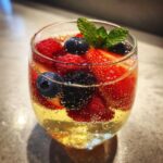 Close-up of Summer Berry White Wine Sangria filled with strawberries, blueberries, raspberries, and mint.