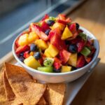 A vibrant bowl of Sweet Fresh Fruit Salsa with cinnamon tortilla chips on the side.