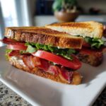 Close-up of The Ultimate BLT Sandwich on Toasted Bread, featuring thick bacon, ripe tomatoes, and lettuce.