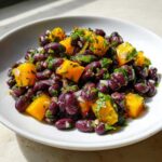 Close-up of Vibrant Black Bean and Mango Salad featuring black beans, bright orange mango chunks, and fresh herbs.