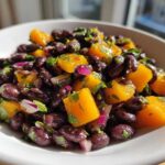 Close-up of Vibrant Black Bean and Mango Salad featuring black beans, bright orange mango chunks, and red onion.