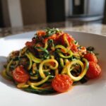 A vibrant plate of Zucchini Noodles (Zoodles) tossed in a rich cherry tomato pesto sauce with whole roasted cherry tomatoes.